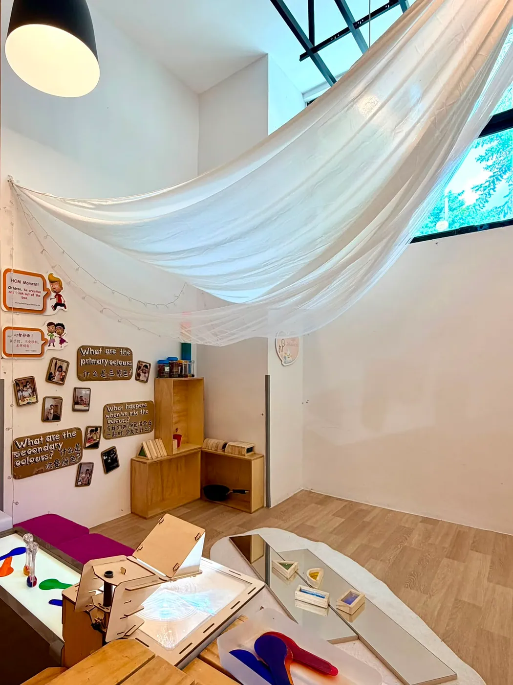 A light table and colour-mixing corner beneath a soft fabric canopy
